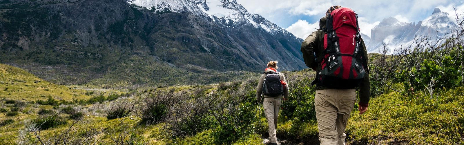 two person walking towards mountain covered with snow