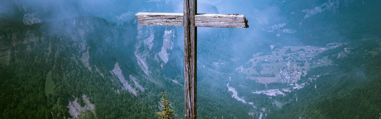 photo of brown wooden cross at cliff