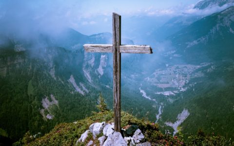photo of brown wooden cross at cliff