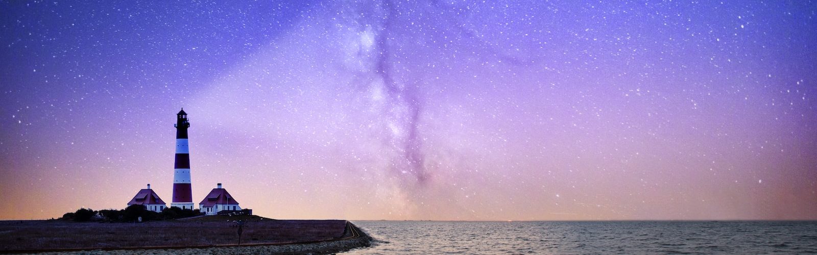 white and red lighthouse near bodies of water at night