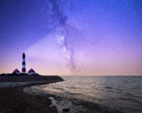 white and red lighthouse near bodies of water at night