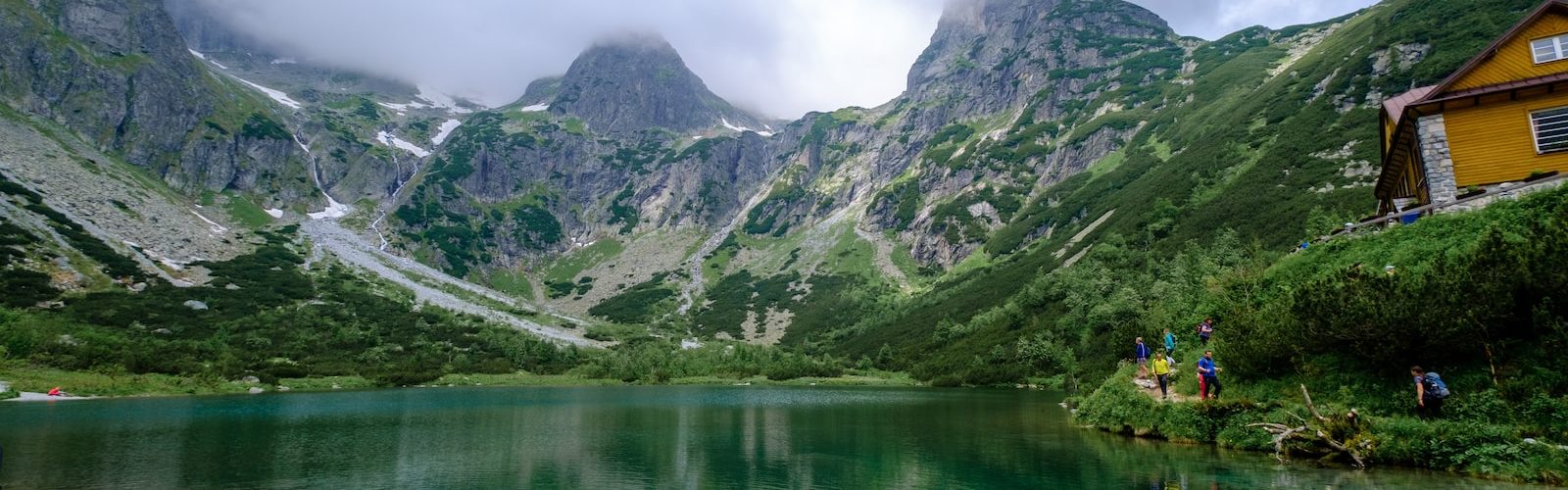 green mountains beside lake under cloudy sky during daytime