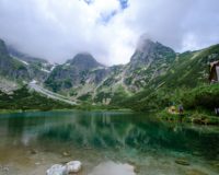 green mountains beside lake under cloudy sky during daytime