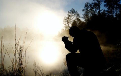 silhouette of kneeling man