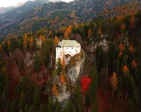 white concrete house on hill surrounded by pine trees