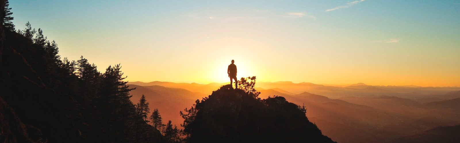 silhouette of man standing on mountain peak