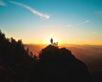 silhouette of man standing on mountain peak