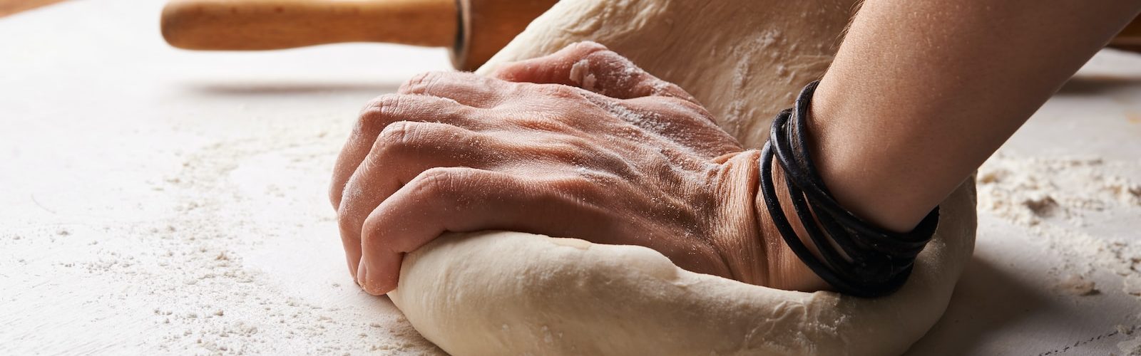 person making dough beside brown wooden rolling pin