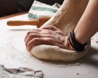 person making dough beside brown wooden rolling pin