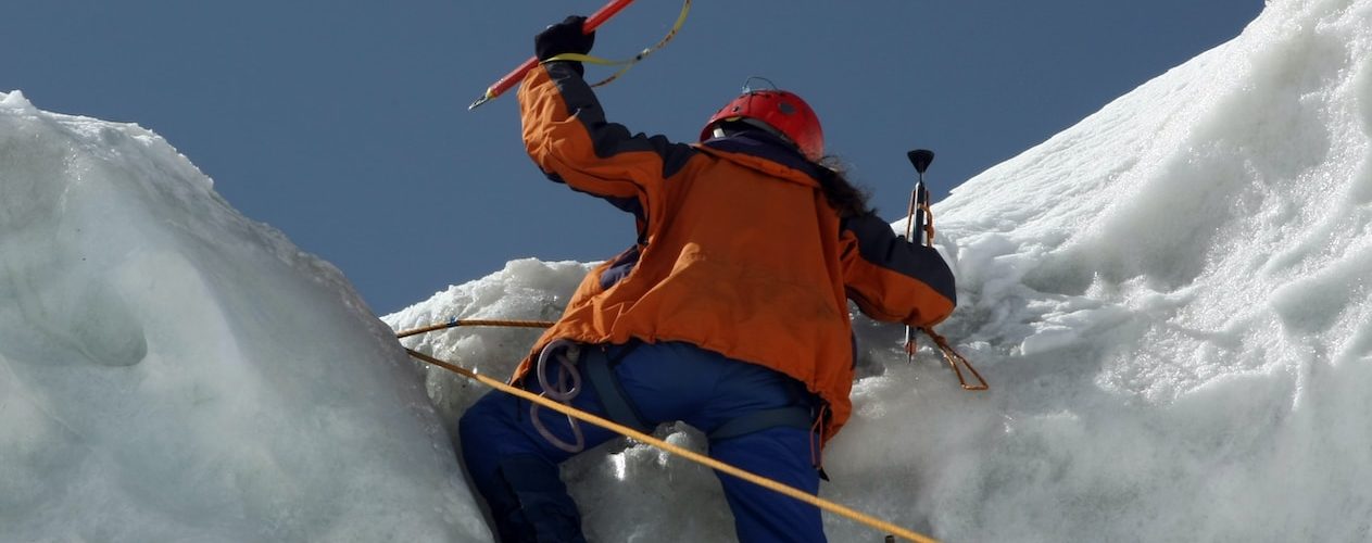 man in orange jacket and blue pants on snow covered mountain during daytime