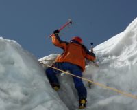 man in orange jacket and blue pants on snow covered mountain during daytime