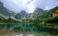 green mountains beside lake under cloudy sky during daytime