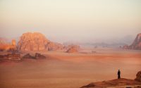 a lone person standing in the middle of a desert