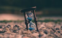 selective focus photo of brown and blue hourglass on stones