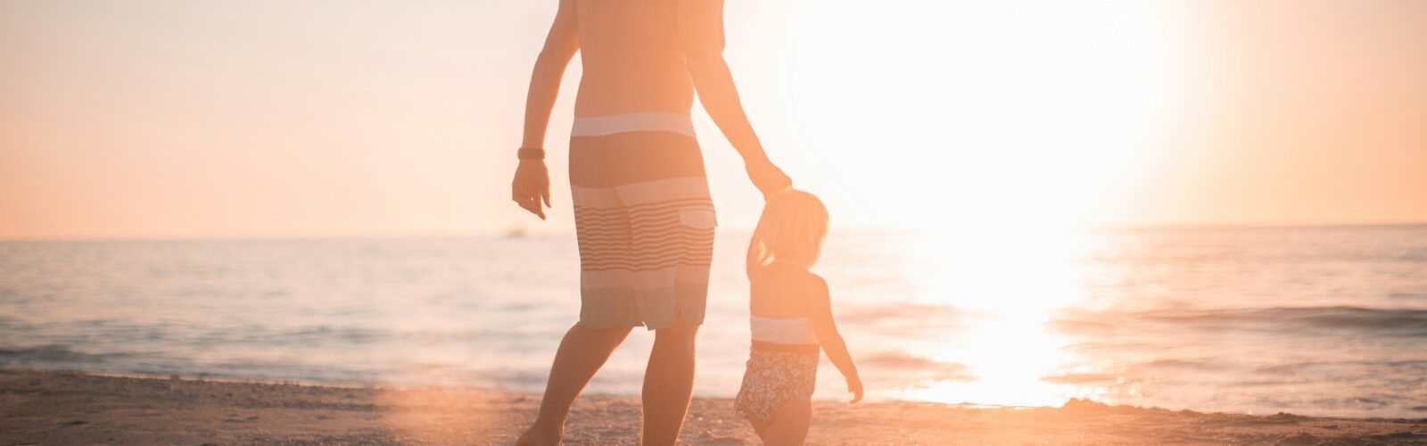 man holding girl heading towards sea