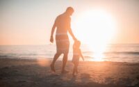 man holding girl heading towards sea