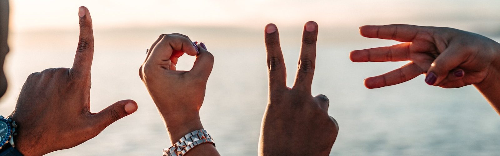 two persons forming love fingers